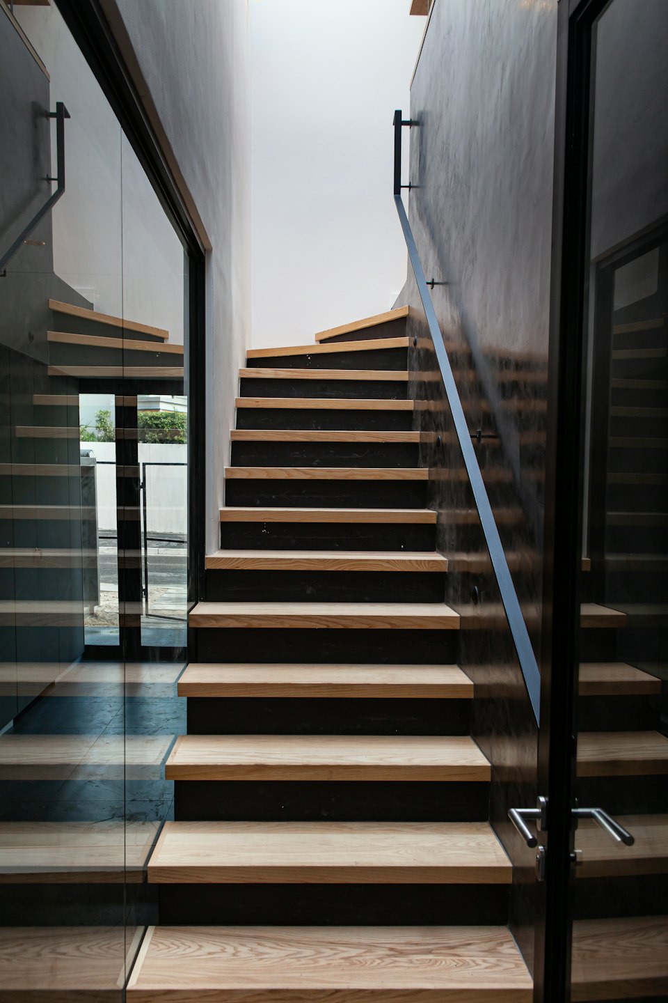 Escalier moderne avec marches en bois et rambarde en verre.