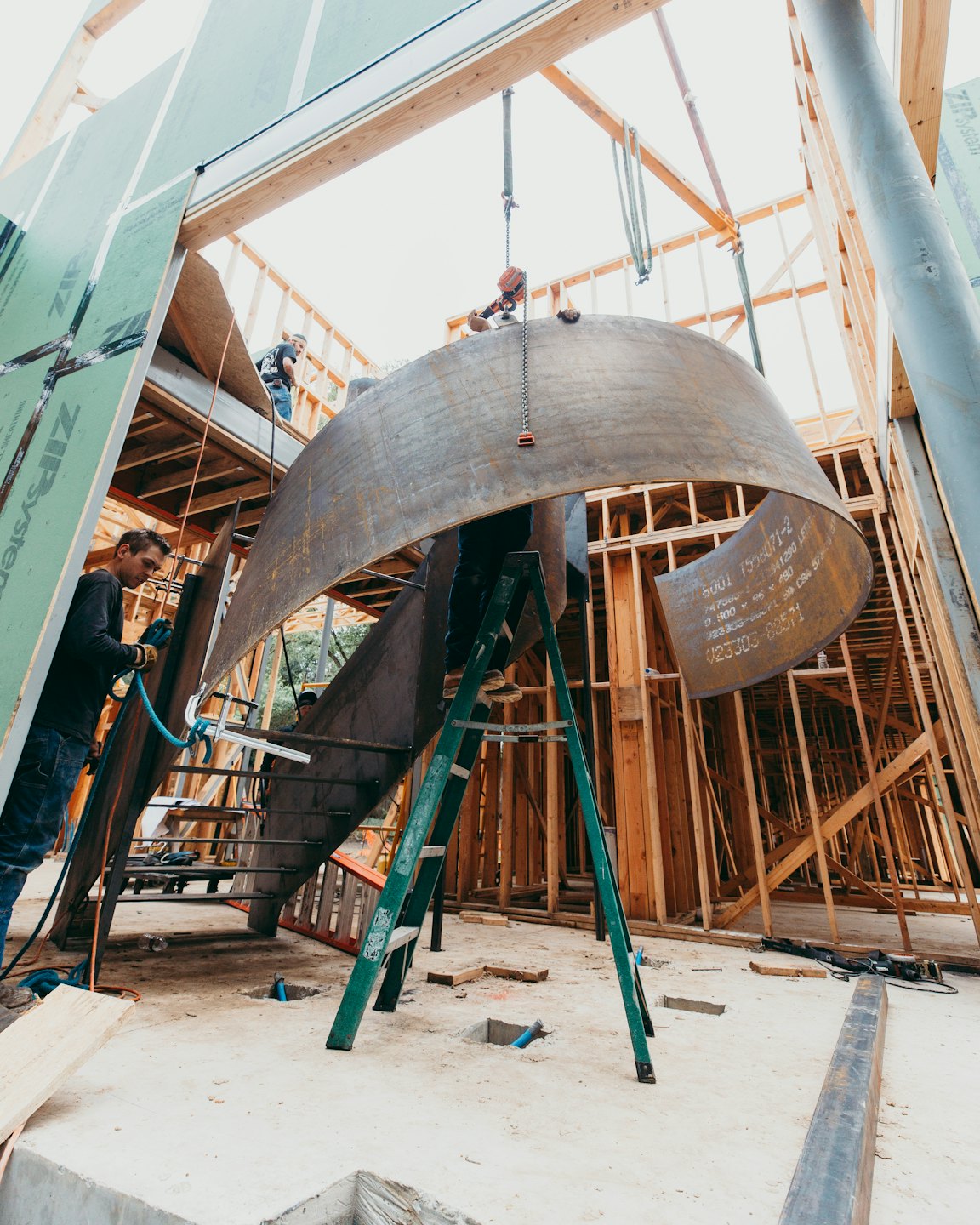 Des ouvriers installent une structure métallique courbée à l'intérieur d'un bâtiment.