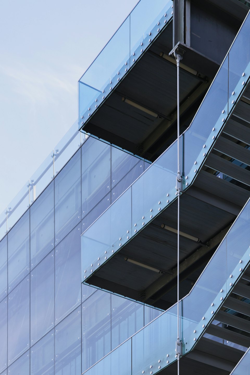 Extérieur d'un bâtiment moderne avec garde-corps en verre et structure en acier.