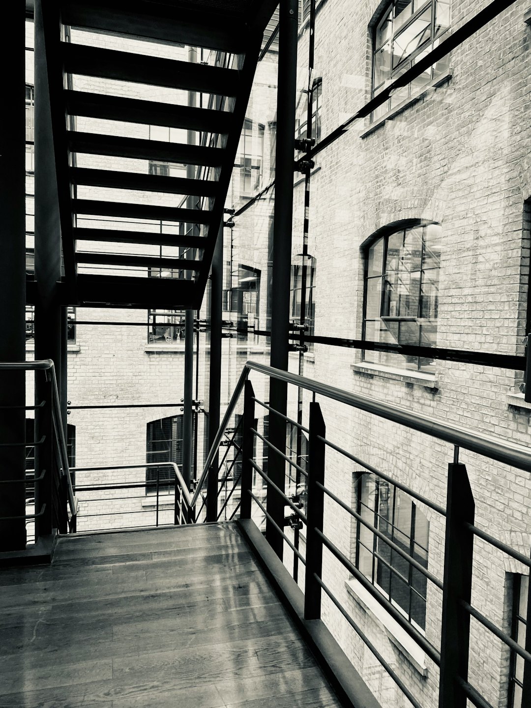 Escalier moderne avec marches en bois sombre et rampes en métal.